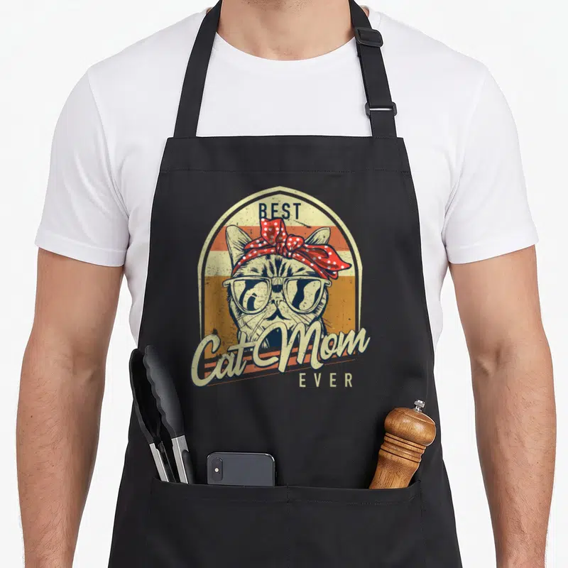 Tablier de cuisine noir avec illustration vintage d'un chat portant un nœud rouge et des lunettes de soleil.