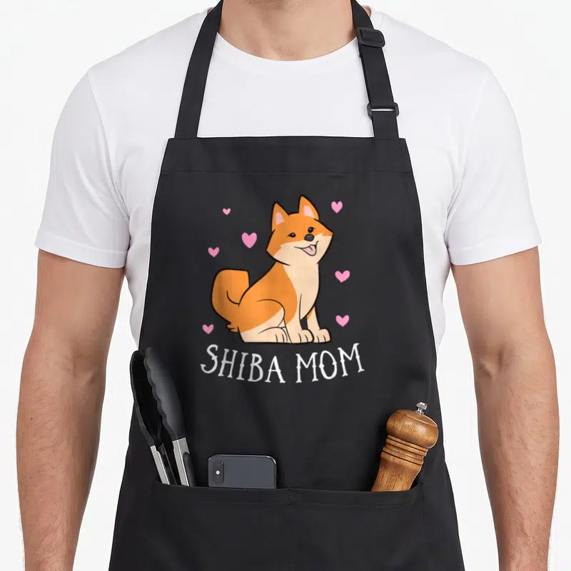 Tablier de cuisine noir avec illustration d'un chien Shiba Inu souriant et texte Shiba Mom en blanc.
