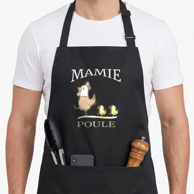 Tablier de cuisine noir avec illustration d'une poule, de deux poussins et du texte Mamie Poule en lettres blanches et beige.