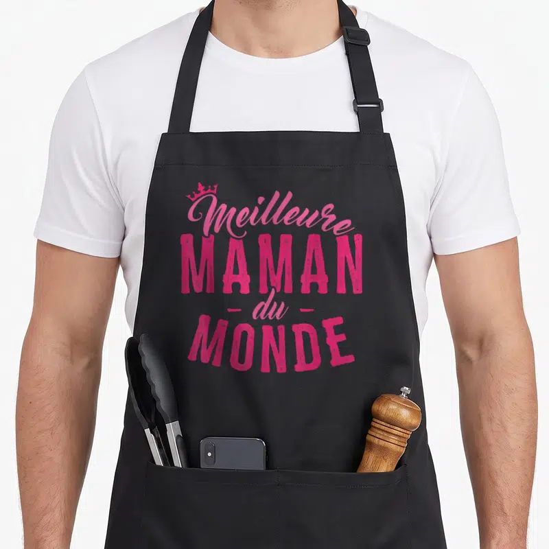 Tablier de cuisine noir avec inscription rose Meilleure Maman du Monde et petite couronne au-dessus.