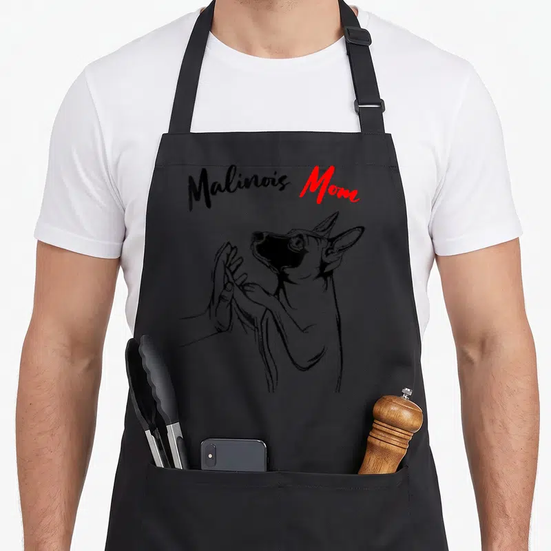 Tablier de cuisine noir avec illustration d'un malinois posant sa patte sur une main humaine sous le texte Malinois Mom.
