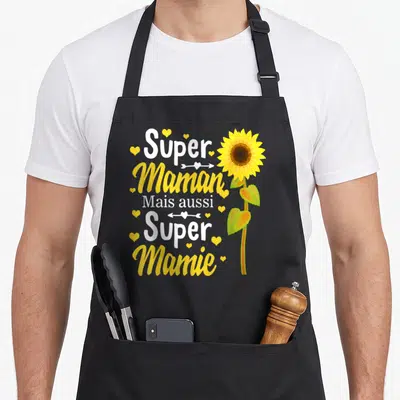 Tablier de cuisine noir avec inscription Super Maman Super Mamie et illustration de tournesol jaune entouré de cœurs.