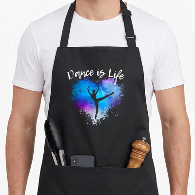 Tablier de cuisine noir avec une ballerine grise sur un cœur bleu et violet et le texte Dance is Life en blanc.