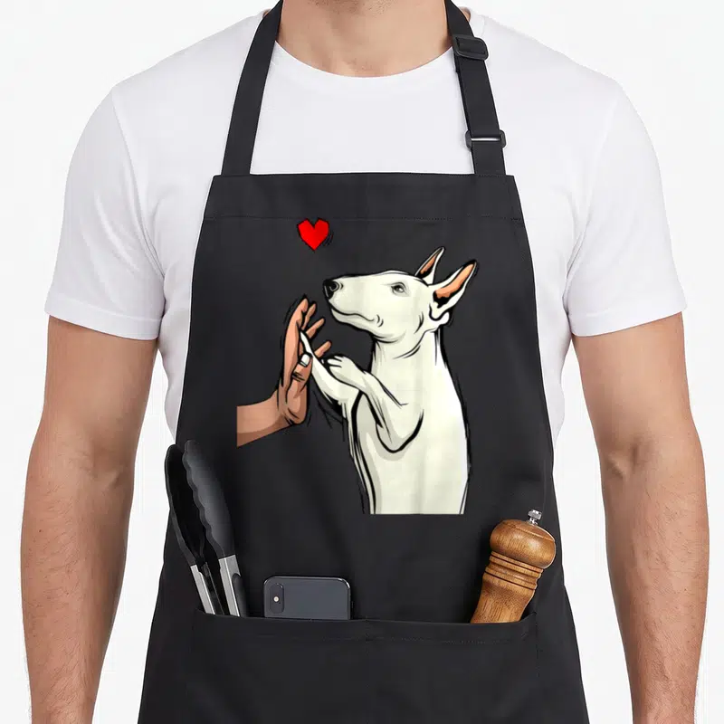 Tablier de cuisine noir avec illustration d'un Bull Terrier blanc et d'une main humaine sous un cœur rouge.