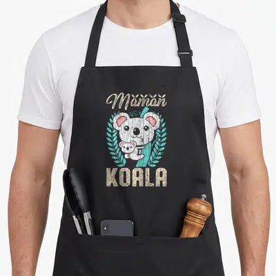 Tablier de cuisine noir avec illustration d'un koala adulte tenant un bébé koala entouré de feuilles turquoise et du texte Maman Koala en lettres beige texturées.