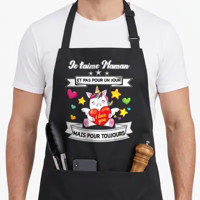 Tablier de cuisine noir avec une licorne colorée tenant un cœur rouge et des étoiles autour, sur fond gris uni.
