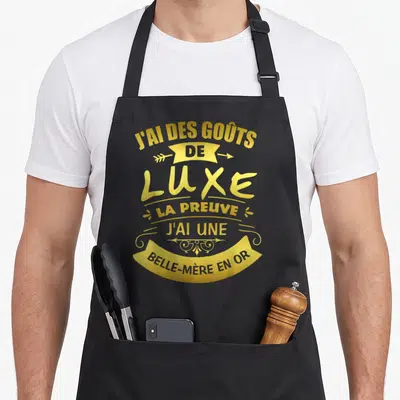 Tablier de cuisine noir avec inscription dorée J'ai des goûts de luxe la preuve j'ai une belle-mère en or et éléments décoratifs.