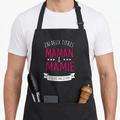 Tablier de cuisine noir avec inscription J'ai deux titres Maman et Mamie et je gère dans les deux en rose et blanc.