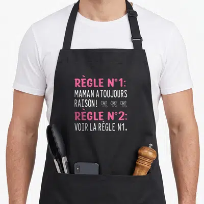 Tablier de cuisine noir avec inscription rose et blanche « Règle n°1 Maman a toujours raison » ornée de trois petits rubans.