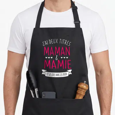 Tablier de cuisine noir avec inscription J'ai deux titres Maman et Mamie et je gère dans les deux en rose et blanc.