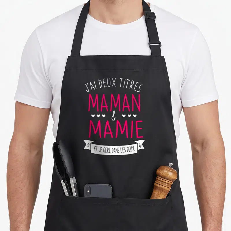 Tablier de cuisine noir avec inscription J'ai deux titres Maman et Mamie et je gère dans les deux en rose et blanc.