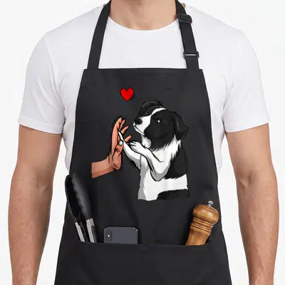 Tablier de cuisine noir avec illustration d'un Border Collie et d'une main se touchant sous un cœur rouge vif.