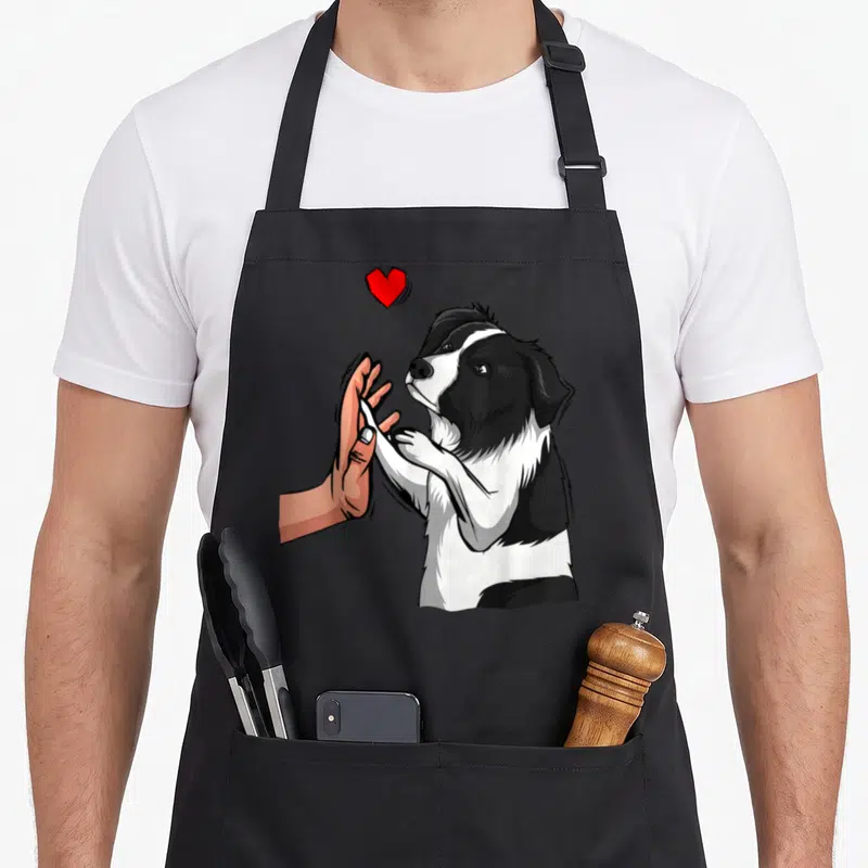 Tablier de cuisine noir avec illustration d'un Border Collie et d'une main se touchant sous un cœur rouge vif.