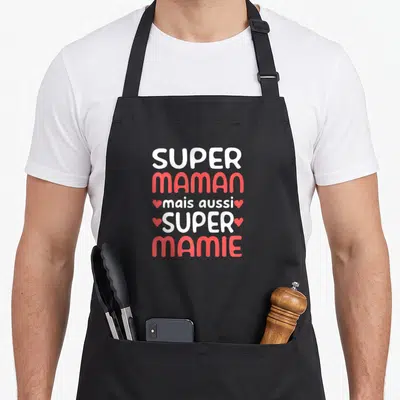 Tablier de cuisine noir avec l'inscription Super Maman mais aussi Super Mamie en blanc et rose accompagnée de petits cœurs.