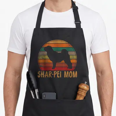 Tablier de cuisine noir avec silhouette de Shar-Pei et texte Shar-Pei Mom sur fond de soleil rayé retro