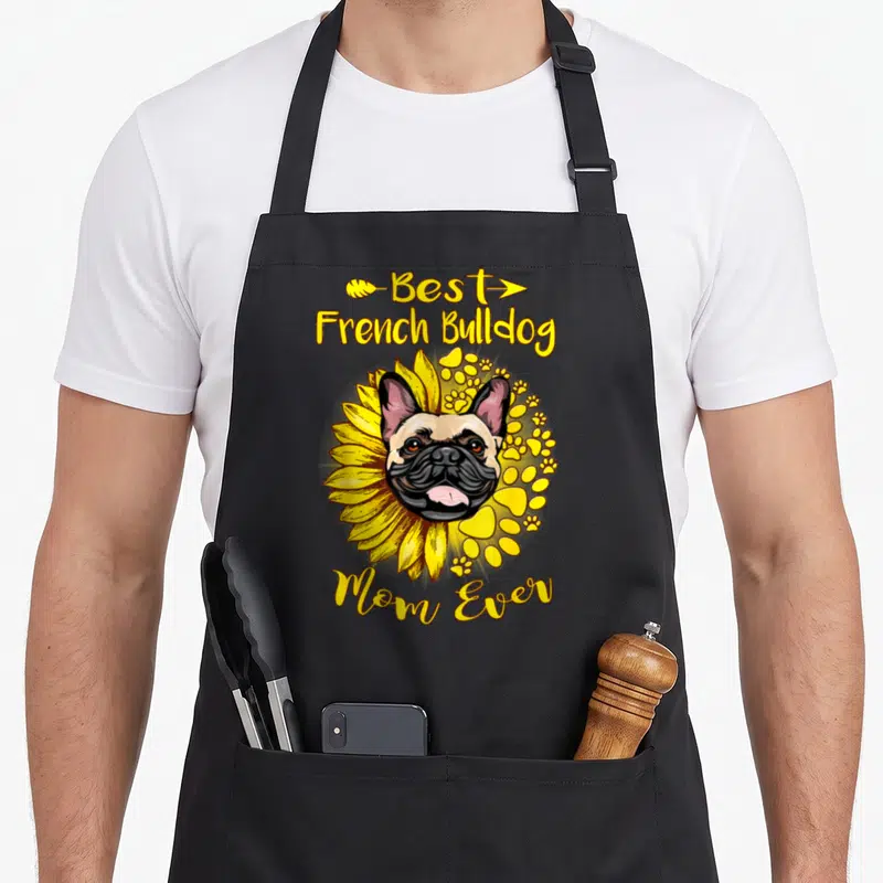 Tablier de cuisine noir avec illustration d'un bouledogue français entouré de fleurs de tournesol jaunes et de traces de pattes.