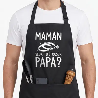 Tablier de cuisine noir avec inscription blanche Maman veux-tu épouser Papa et illustration d'anneaux de mariage.