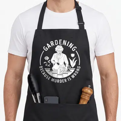 Tablier de cuisine noir avec illustration blanche d'une femme arrosant des fleurs et le texte Gardening Because Murder Is Wrong.