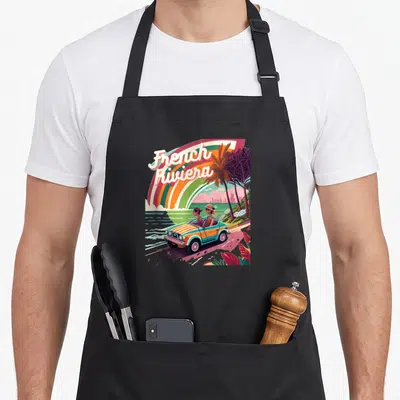 Tablier de cuisine noir avec illustration rétro French Riviera montrant une voiture sur la côte méditerranéenne.