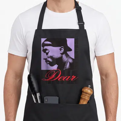 Tablier de cuisine noir avec portrait de Tupac, texte Dear Mama en rouge et You Are Appreciated verticalement.