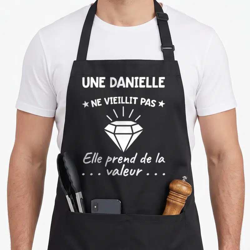 Tablier de cuisine noir avec une illustration de diamant blanc et le texte Une Danielle ne vieillit pas Elle prend de la valeur.