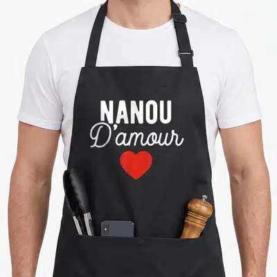 Tablier de cuisine noir avec l'inscription Nanou D'amour en blanc et un cœur rouge au centre.