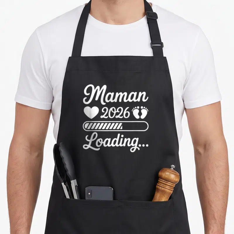 Tablier de cuisine noir avec inscription Maman 2026 Loading et icônes blanches sur fond uni.