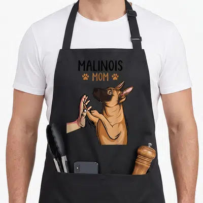 Tablier de cuisine noir avec illustration d'un malinois et d'une main en high five, texte Malinois Mom.