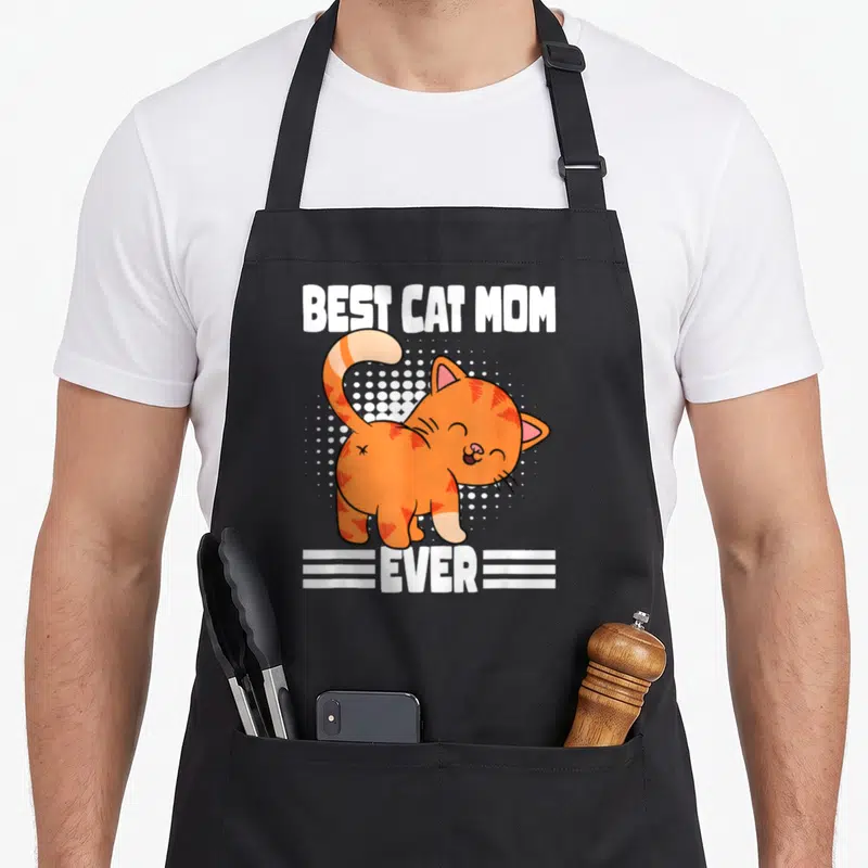 Tablier de cuisine noir avec illustration d'un chat orange souriant et le texte Best Cat Mom Ever en blanc.