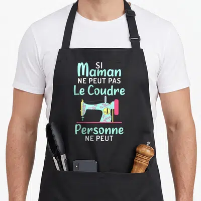 Tablier de cuisine noir avec une machine à coudre turquoise et le texte Si Maman ne peut pas le coudre personne ne peut.