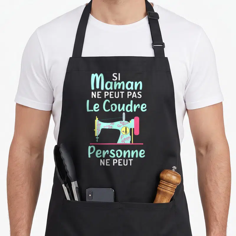 Tablier de cuisine noir avec une machine à coudre turquoise et le texte Si Maman ne peut pas le coudre personne ne peut.