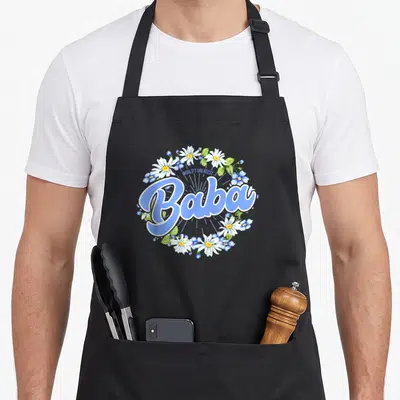 Tablier de cuisine noir avec l'inscription World's Greatest Baba entourée de marguerites et de bleuets bleus.