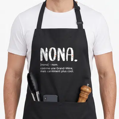 Tablier de cuisine noir avec le mot Nona en lettres remplies de fleurs et une définition humoristique en blanc.