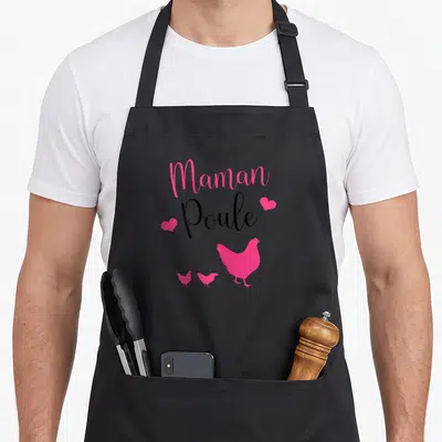 Tablier de cuisine noir avec inscription Maman Poule, silhouettes roses de poules et petits cœurs décoratifs.