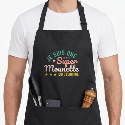 Tablier de cuisine noir avec l'inscription Je Suis Une Super Mounette Qui Déchiiiiiire en lettres colorées et étoiles jaunes.