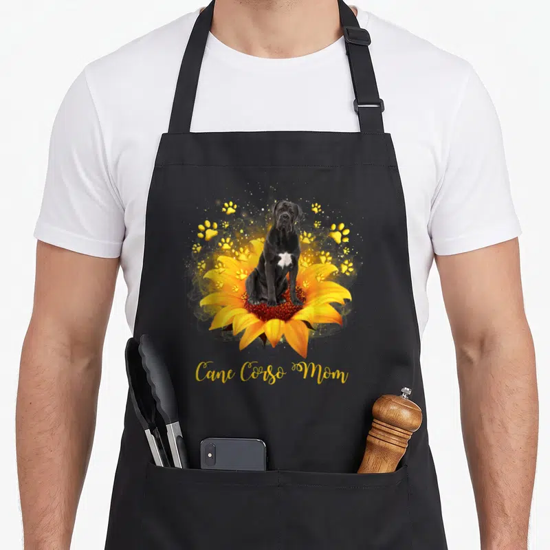 Tablier de cuisine noir avec un chiot Cane Corso sur une fleur de tournesol et des traces de pattes dorées.
