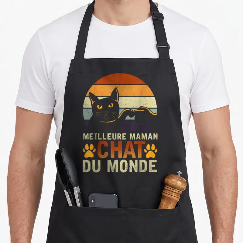 Tablier de cuisine noir avec silhouette de chat, patte orange et texte meilleure maman chat du monde en style vintage.