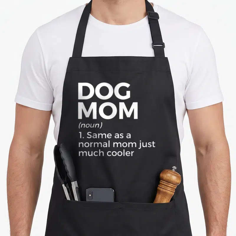 Tablier de cuisine noir avec l'inscription blanche Dog Mom et sa définition humoristique en anglais.