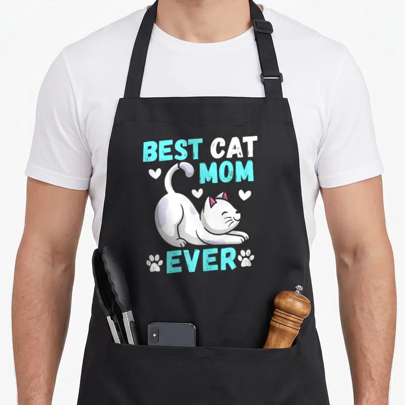 Tablier de cuisine noir avec un chat blanc s'étirant sous le texte Best Cat Mom Ever et des empreintes de pattes.