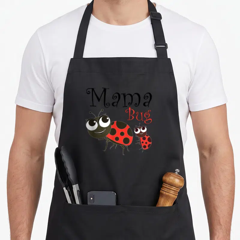 Tablier de cuisine noir avec l'inscription Mama Bug et deux coccinelles rouges souriantes aux grands yeux ronds.