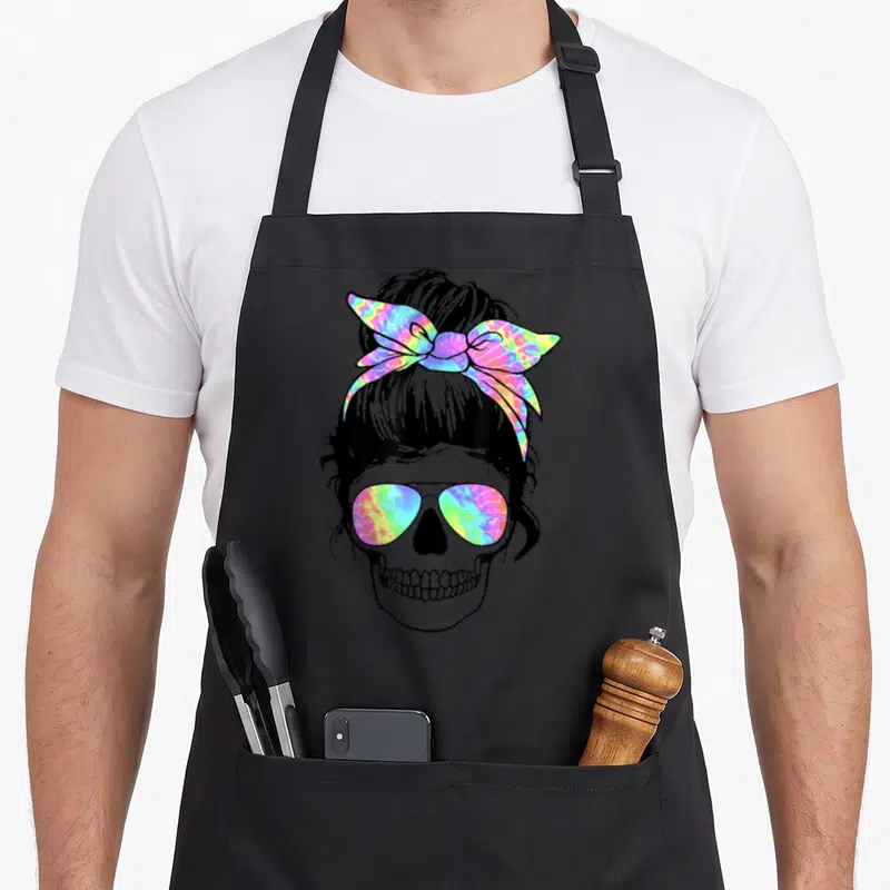 Tablier de cuisine noir avec un crâne portant des lunettes et un chignon arc-en-ciel tie-dye