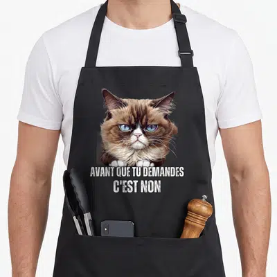 Tablier de cuisine noir avec illustration de chat fâché et texte blanc Avant que tu demandes c'est non même