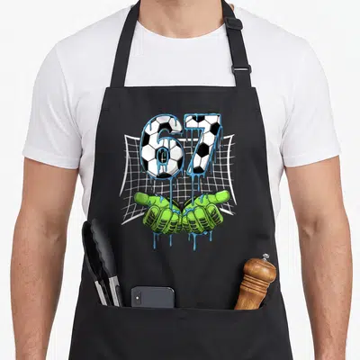 Tablier de cuisine noir avec les chiffres 67 en motif de ballon de football et des gants de gardien de but verts.