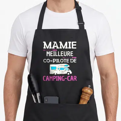 Tablier de cuisine noir avec texte Mamie meilleure co-pilote camping-car et illustration de véhicule blanc aux fenêtres bleues.