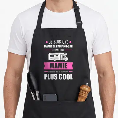 Tablier de cuisine noir avec illustration de camping-car et texte blanc et rose sur fond uni