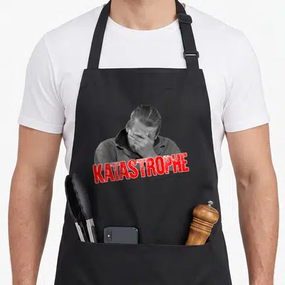 Tablier de cuisine noir avec homme en noir et blanc se couvrant le visage et le mot KATASTROPHE en rouge.