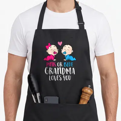 Tablier de cuisine noir avec deux bébés roses et bleus et le texte Pink or Blue Grandma Loves You.