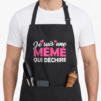 Tablier de cuisine noir avec le texte Je suis une Mémé qui déchire en rose et blanc orné de petits cœurs.