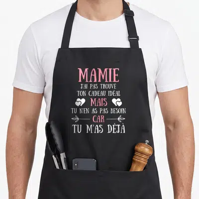 Tablier de cuisine noir avec texte rose et blanc Mamie j'ai pas trouvé ton cadeau idéal mais car tu m'as déjà orné de deux cœurs blancs.
