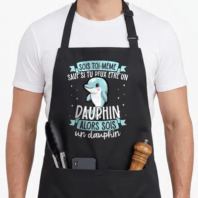 Tablier de cuisine noir avec illustration d'un dauphin bleu souriant et texte humoristique en blanc et bleu clair.